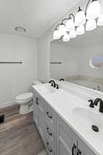 Bathroom with double vanity, a textured ceiling, and dark wood finished floors