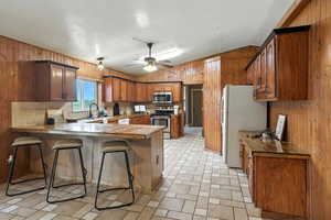 Kitchen featuring a peninsula, wooden walls, lofted ceiling, brown cabinets, and a kitchen breakfast bar