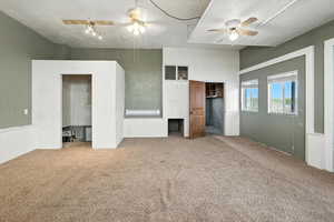 Unfurnished bedroom with carpet floors, ceiling fan, and a towering ceiling
