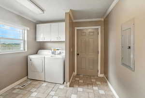 Laundry area featuring electric panel, cabinet space, independent washer and dryer, stone finish flooring, and crown molding