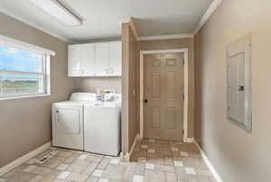 Laundry room with electric panel, cabinet space, washer and dryer, and crown molding