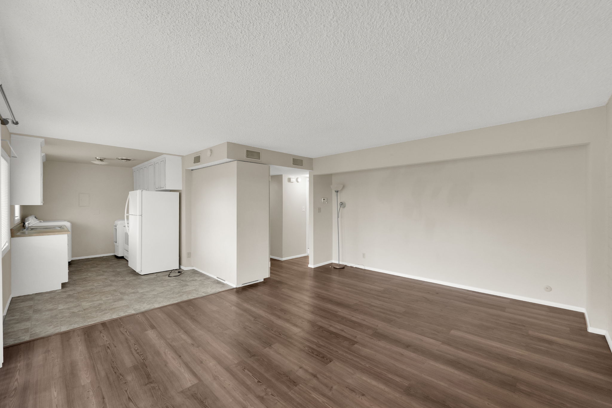 Unfurnished living room featuring dark wood-type flooring and a textured ceiling