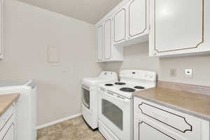 Kitchen featuring white electric range, white cabinetry, and light countertops