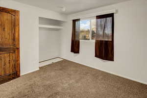 Unfurnished bedroom with carpet flooring and baseboards