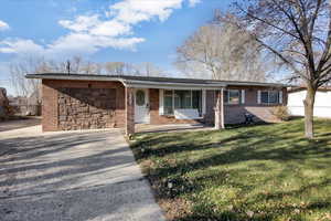 Single story home with covered porch, a front lawn, and brick siding