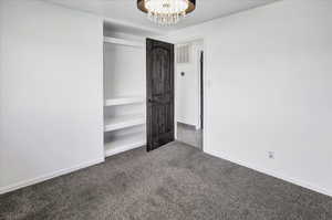 Unfurnished bedroom with carpet floors, a closet, and a chandelier