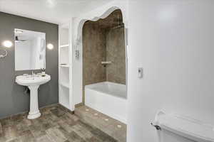 Full bathroom with a textured ceiling, wood finished floors, bathtub / shower combination, and built in shelves