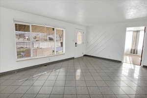 Empty room featuring a textured ceiling and healthy amount of natural light