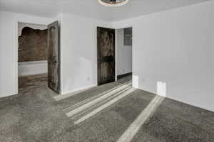 Unfurnished bedroom featuring a textured ceiling, carpet floors, and connected bathroom
