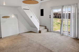 Unfurnished living room with stairway and carpet flooring