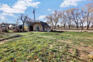 View of front of home with stone siding, a gambrel roof, and an outdoor structure