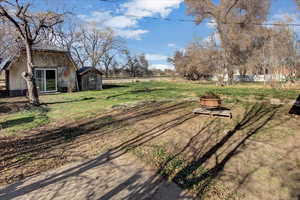 View of yard with an outdoor fire pit and a shed