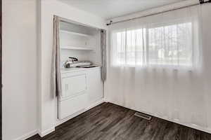 Laundry room with dark wood-type flooring and washing machine and dryer