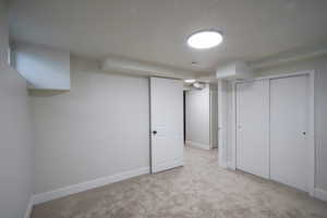 Finished below grade area featuring light carpet and baseboards