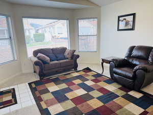 Living room with tile patterned floors, carpet floors, and lofted ceiling