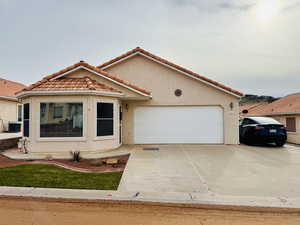 Mediterranean / spanish-style home featuring a tile roof, stucco siding, concrete driveway, and an attached garage