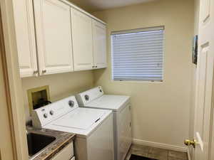 Laundry room featuring cabinet space, washer and clothes dryer, and dark tile patterned flooring