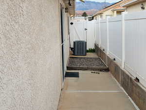 View of side of home with stucco siding, a patio, a mountain view, and a gate