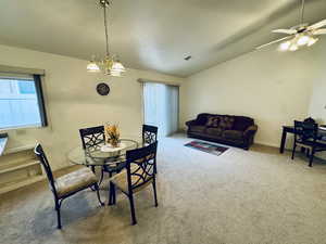 Dining area with lofted ceiling, carpet flooring, a textured ceiling, and a chandelier