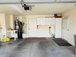 Garage featuring secured water heater and a garage door opener