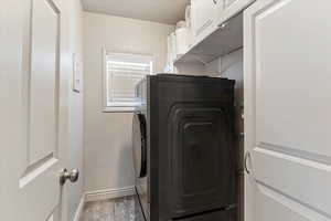 Laundry area featuring cabinet space, light wood finished floors, and a textured ceiling