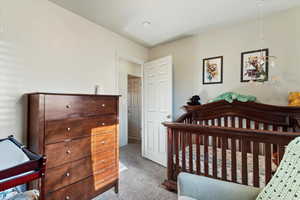 Bedroom with a crib and light carpet