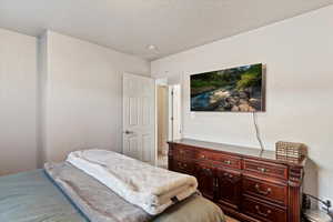 Bedroom with a textured ceiling and light carpet