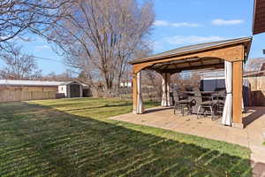Fenced backyard featuring a storage shed, a gazebo, and a patio area