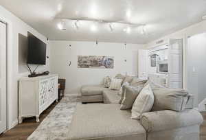 Living area with rail lighting, wood finished floors, and a textured ceiling
