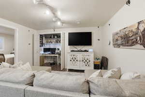 Living room with an office area, track lighting, a textured ceiling, and wood finished floors