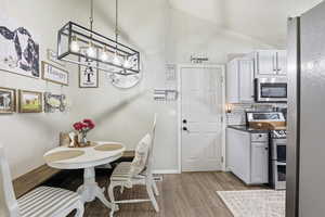 Dining space featuring vaulted ceiling and light wood finished floors