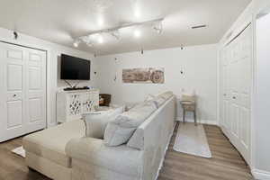 Living area with wood finished floors, a textured ceiling, and track lighting