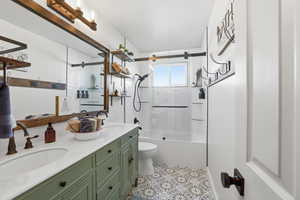 Bathroom with double vanity, combined bath / shower with glass door, and light tile patterned floors
