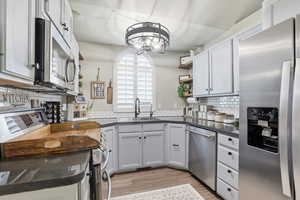 Kitchen featuring open shelves, stainless steel appliances, backsplash, and light wood finished floors