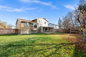 Back of house with a fenced backyard, a gate, and a sunroom