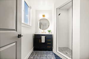 Bathroom with vanity, a shower stall, and dark tile patterned flooring