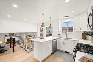 Kitchen featuring open floor plan, recessed lighting, white cabinets, a peninsula, and light wood-style flooring