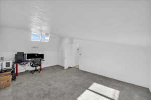 Office area with a textured ceiling, carpet, and lofted ceiling