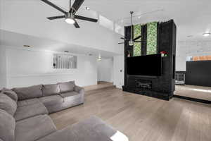 Living area featuring light wood-style floors, a towering ceiling, track lighting, ceiling fan, and an accent wall