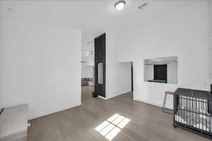 Unfurnished living room featuring light wood-type flooring, a fireplace, and a towering ceiling