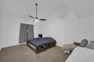 Bedroom featuring wood finished floors, a ceiling fan, and high vaulted ceiling