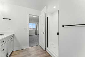 Full bathroom with vanity, a stall shower, and light wood-style floors
