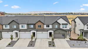 View of front facade featuring a shingled roof, a residential view, concrete driveway, a garage, and a mountain view