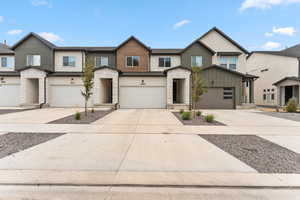 View of front of home with stone siding, driveway, a garage, and stucco siding