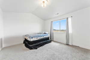 Bedroom featuring lofted ceiling and light colored carpet