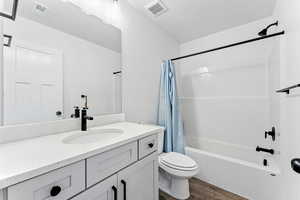 Full bath featuring shower / bath combination with curtain, vanity, and dark wood-style flooring