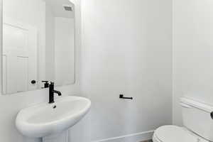 Half bathroom with a sink and baseboards