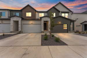 View of front of property featuring stone siding, driveway, and board and batten siding