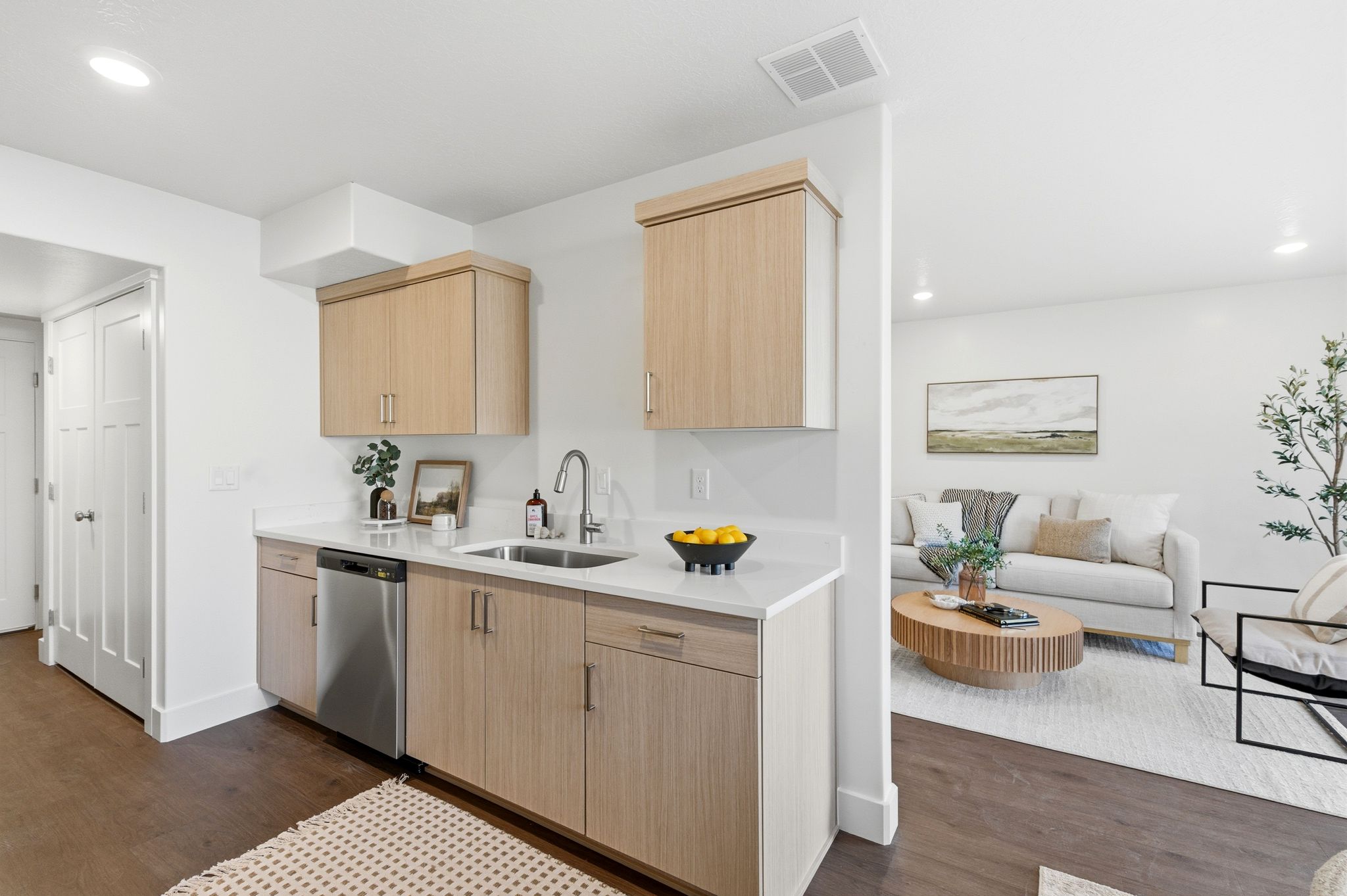 Kitchen with light brown cabinets, recessed lighting, dark wood finished floors, dishwasher, and light stone countertops