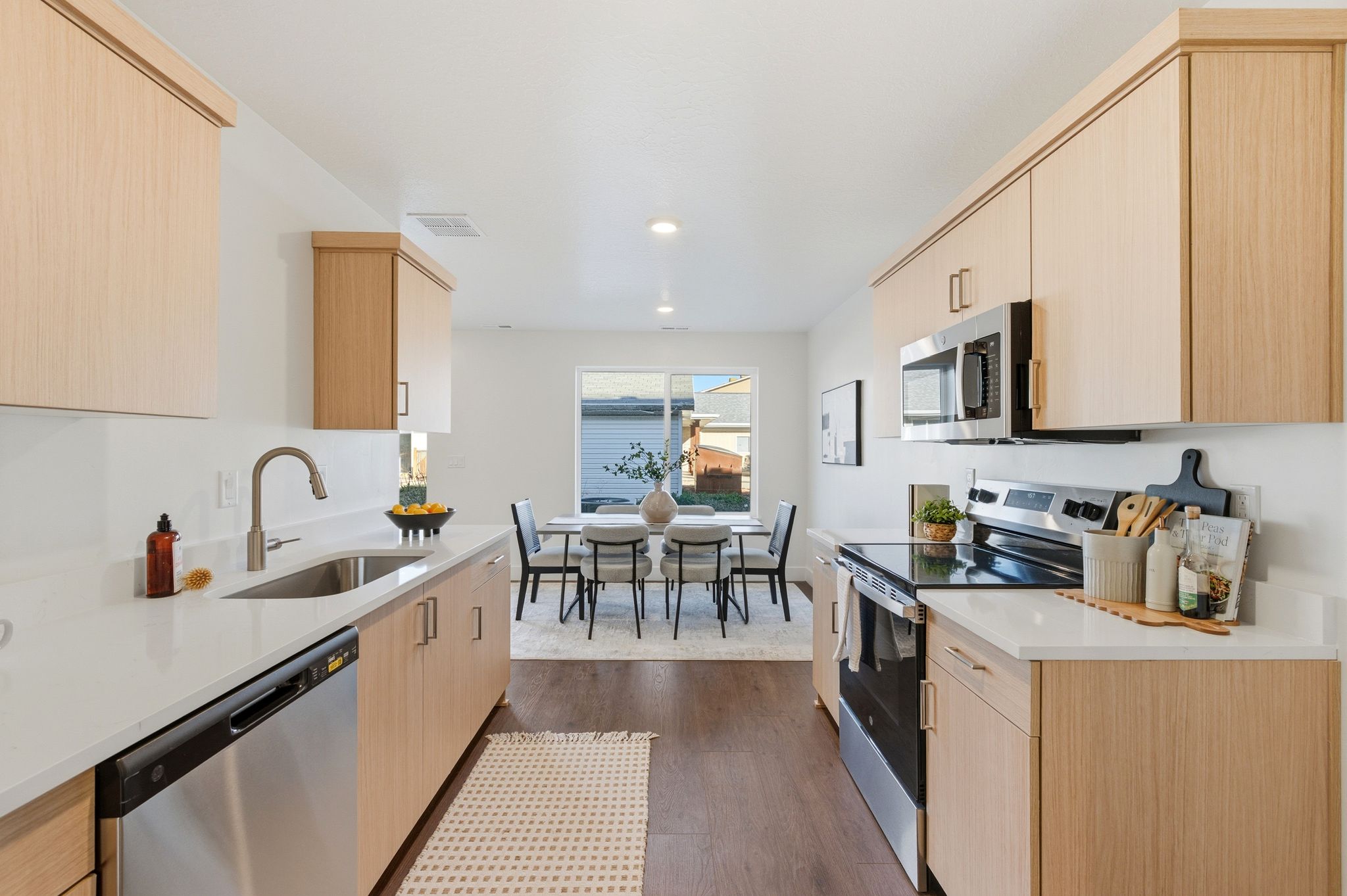 Kitchen featuring light brown cabinetry, stainless steel appliances, light stone countertops, dark wood-style floors, and recessed lighting